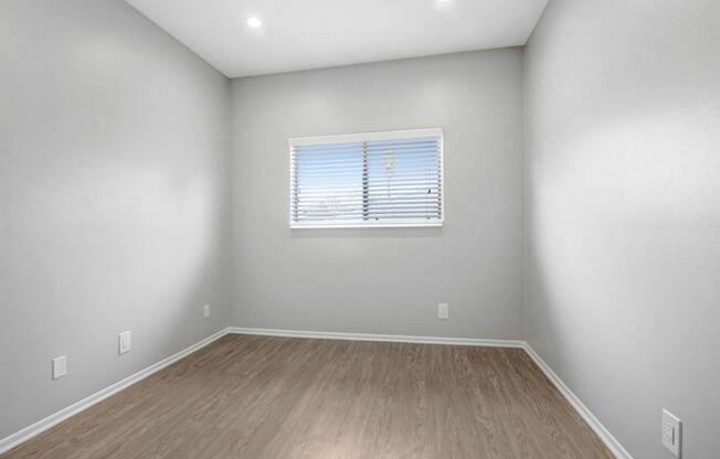 the living room of an empty home with wood floors and a window