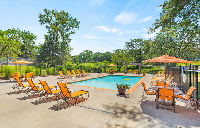 a swimming pool with orange chairs and umbrellas