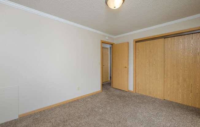 a bedroom with a closet and carpeted floors. Fargo, ND Birchwood 2 Apartments