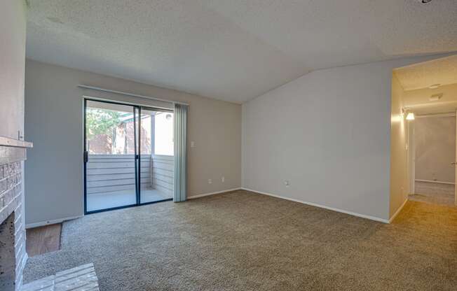 an empty living room with a fireplace and a sliding glass door