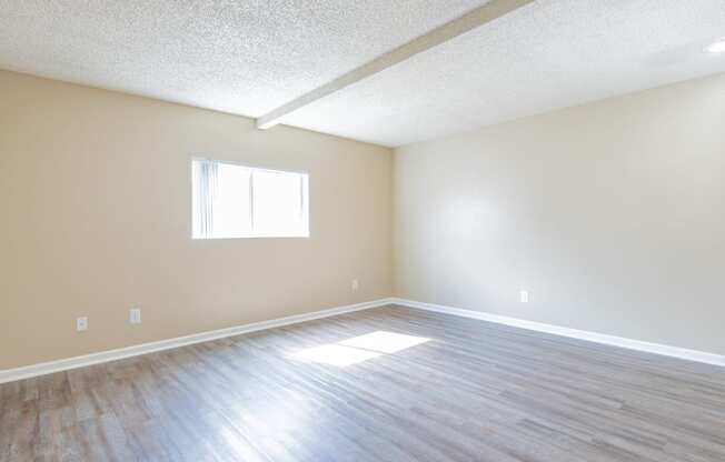 an empty living room with wood floors and a window