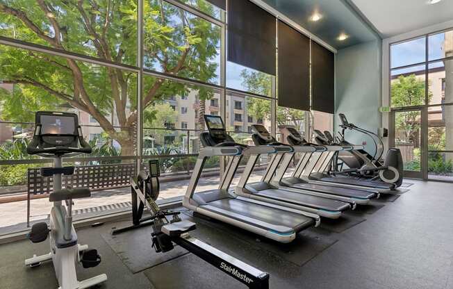 A gym with treadmills, elliptical machines, and a rowing machine at The Kitt at Warner Center Apartments, Woodland Hills, CA, 91303