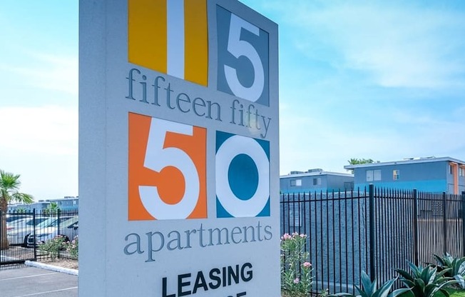Fifteen 50 apartments in Las Vegas modern concrete street sign on lush landscaping next to parking lot and gated apartments.