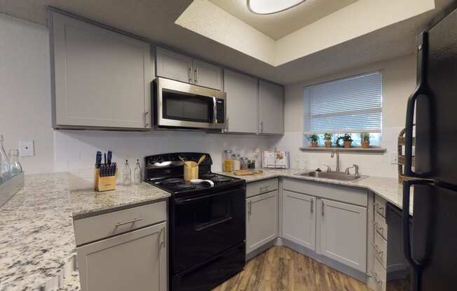 a kitchen with white cabinets and black appliances and granite counter tops