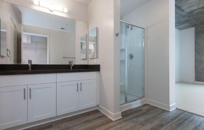 Oakland CA Apartments-Aqua Via Apartments Bathroom With Glass Door Shower And Double Sink Vanity And Vinyl Plank Flooring