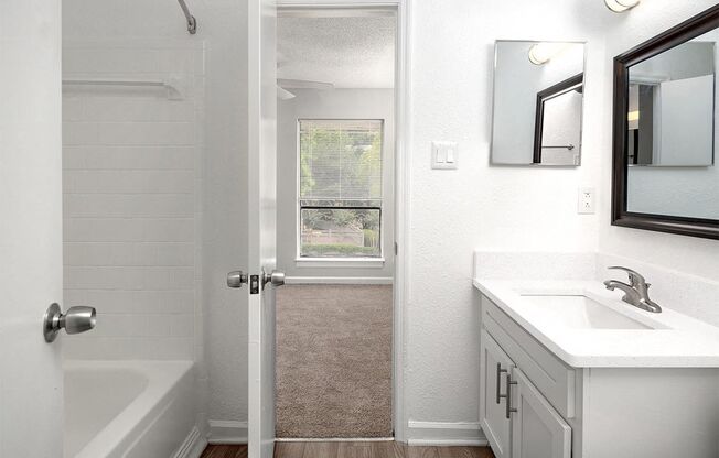 an empty bathroom with a sink and a shower and a window