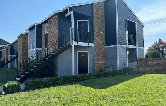 an apartment building with a green lawn and a staircase