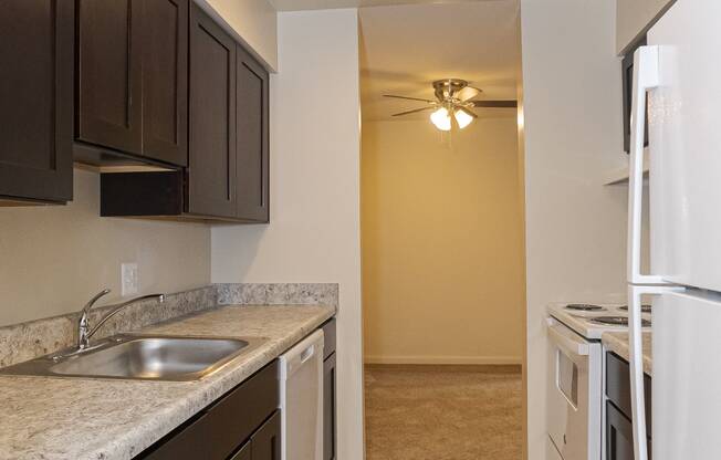 a kitchen with dark cabinets and a white refrigerator and a sink