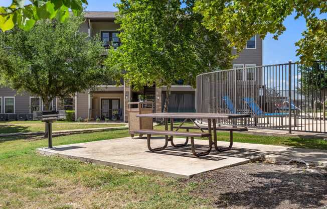 a picnic table in a park with a playground in the background