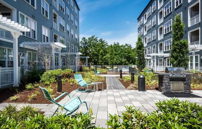 a patio with a fire pit and lounge chairs in front of a building