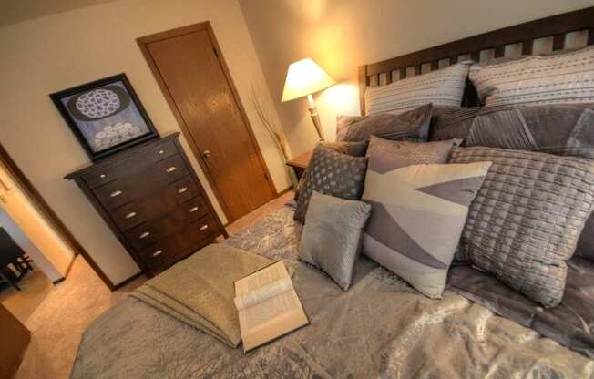 a bedroom with a bed with pillows and a dresser