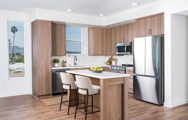 Premium finish kitchens feature quartz countertops, wood-grain cabinetry, stainless steel appliances, and an oversized island with integrated seating.