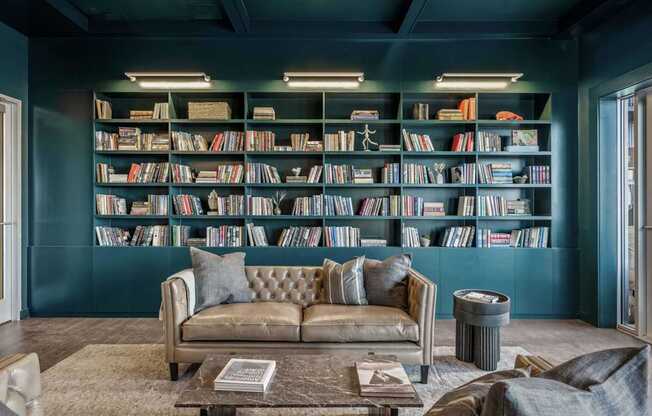 A living room with a couch, a coffee table, and a bookshelf filled with books.