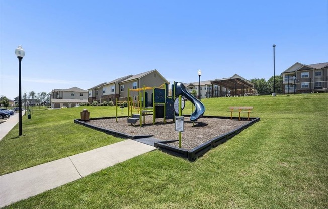 a playground with a blue slide in front of some apartments at The Maddox Apartments, Centerton, Arkansas