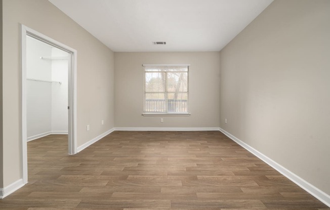 an empty living room with wood flooring and a window