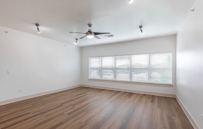 A room with a ceiling fan and wooden flooring.