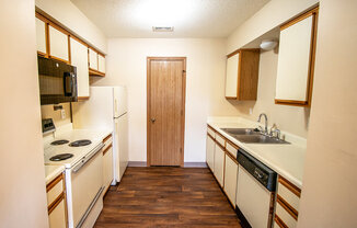 A kitchen with a white fridge, black stove, and wooden cabinets.