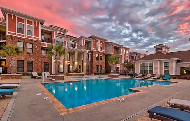 a swimming pool in front of an apartment building with a blue pool at Nexus at Sandhill, Columbia, SC