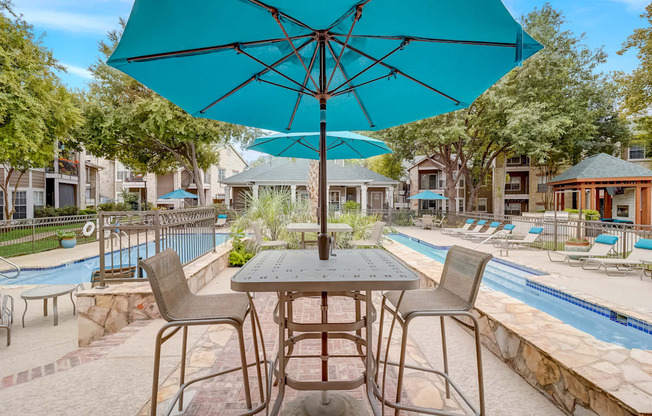 a patio with tables and umbrellas next to a swimming pool