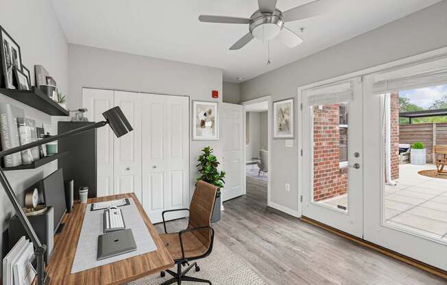 A room with a desk, chair, and a ceiling fan.