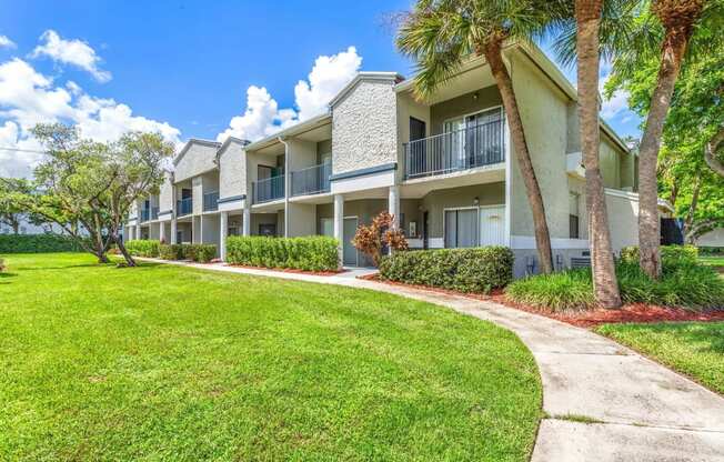 a sidewalk in front of an apartment building with palm trees at Waterford Park Apartment Homes, LLC, Lauderhill, FL 33319