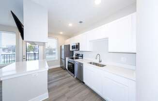A modern kitchen with white cabinets and stainless steel appliances.