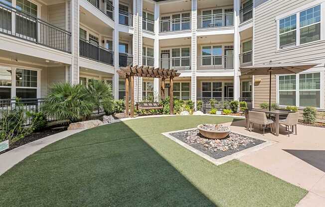 A courtyard with a fire pit and seating area in front of a building.