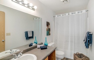 A bathroom with a white shower curtain and a white toilet.at Alder Creek Apartments, Washington