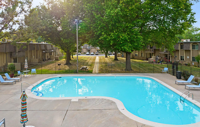 a swimming pool with chairs around it and trees