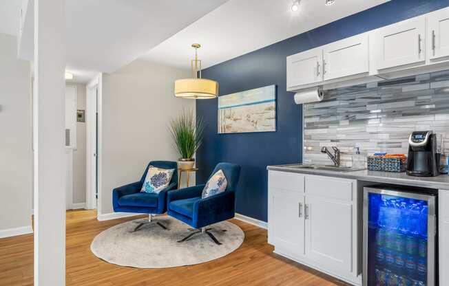 Clubhouse area with two blue chairs and a kitchen with a sink