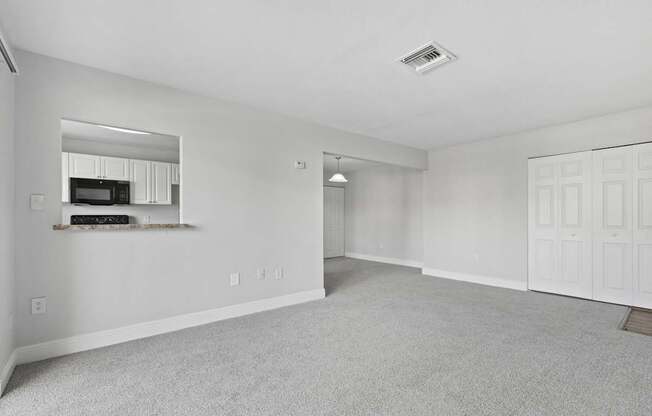 A spacious living room with a grey carpet and white walls.