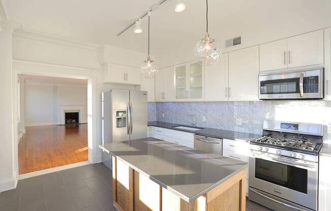 Kitchen with slate tile flooring, white cabinets, island and pendant lights at York House, Missouri, 63108