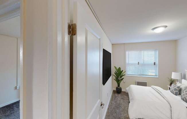 bedroom with bed, nightstand, tv, window and lighting at manor village apartments in washington dc