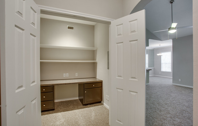 View of Closet with Desk, Ceiling Fan, and View of Living Room at Raveneaux Apartments