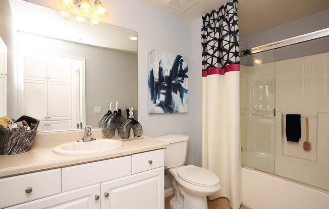A bathroom with a white toilet, sink, and shower. at The Kitt at Warner Center Apartments, Woodland Hills, CA