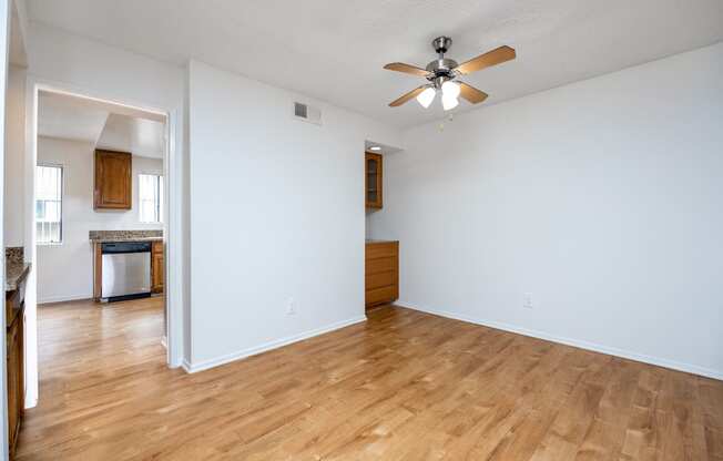 the living room and dining room of an empty house with a ceiling fan