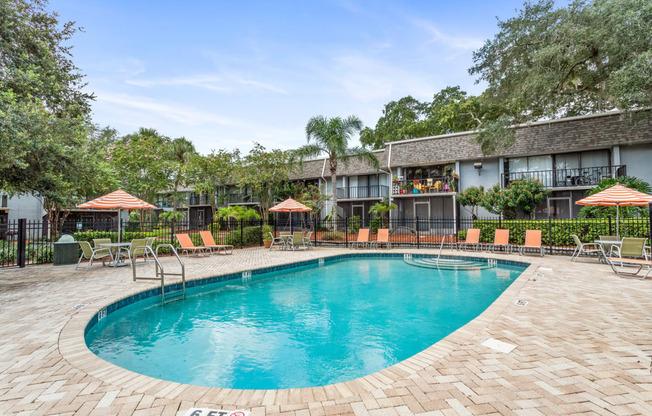 a resort style pool with chairs and umbrellas in front of a building