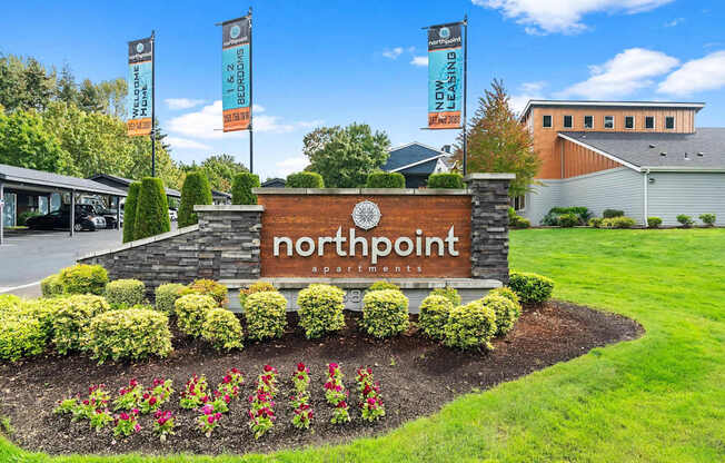A sign for Northpoint Apartments is surrounded by flowers and greenery. at Northpoint Apartments, Tacoma, Washington