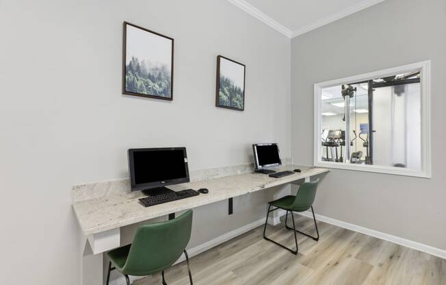 two computers on a desk in a room with a window