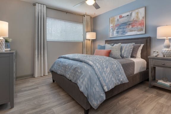large bedroom with illuminated ceiling fan, hardwood-inspired flooring, model furnishings at Preserve at Cedar River Apartments, Jacksonville, FL