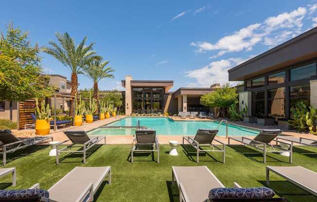 A pool surrounded by lounge chairs and palm trees.