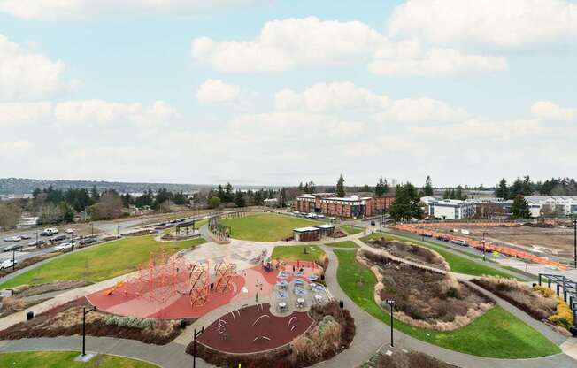 A playground with a red slide and a green hill.
