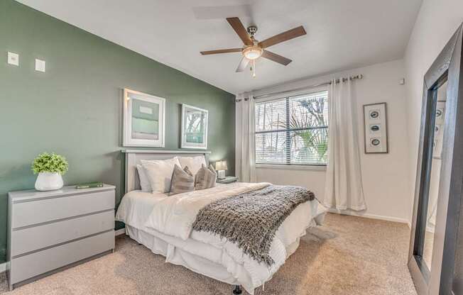 A bedroom with a bed, dresser, and window.