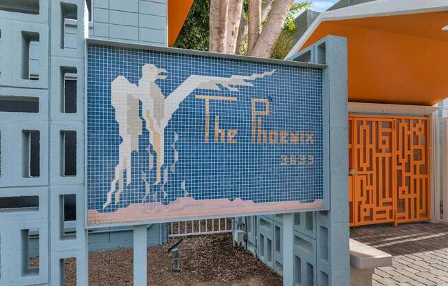 A blue tiled mosaic of a man holding a bird with the words at The Phoenix Apartments on 6th Avenue, Arizona