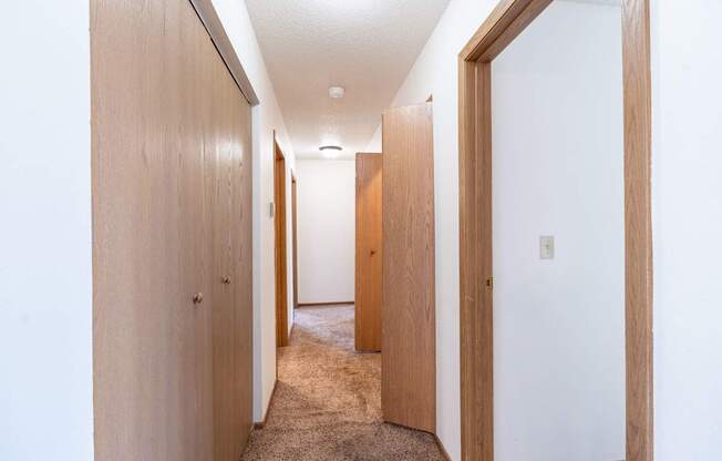 A hallway with wooden doors and carpeted floor.