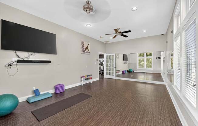 Yoga room with large windows, ceiling fans, mat, mirrored wall and free weight