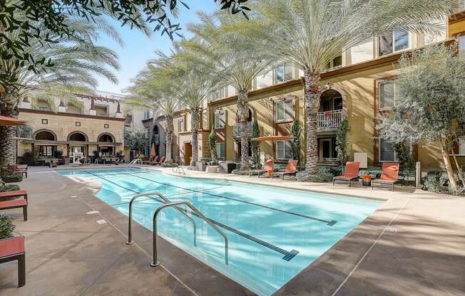 a swimming pool with lounge chairs under palm tress