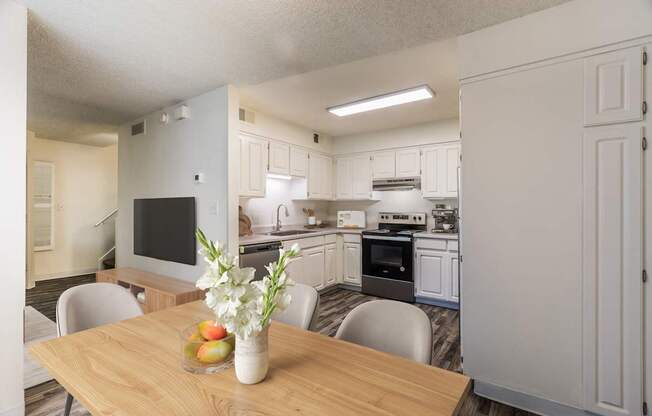 A kitchen with a table and chairs in front of it.