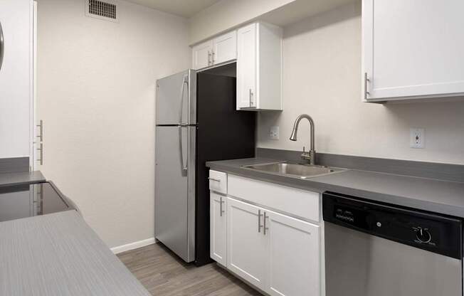 A small kitchen with a black refrigerator and white cabinets.