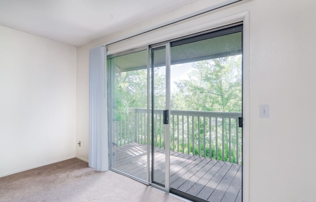 an empty living room with sliding glass doors to a balcony